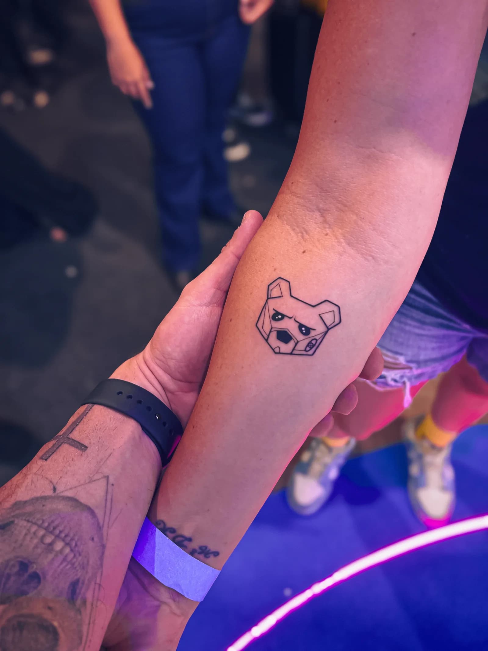 Will Jardim segurando o antebraço de um fã que tatuou o urso mascote da Under Labz